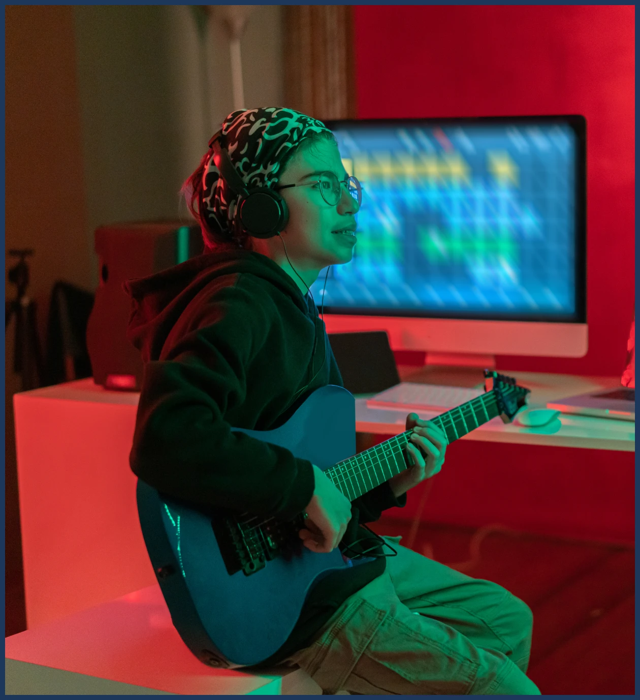 Person playing guitar with headphones in studio